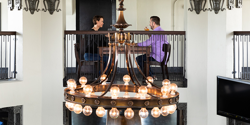 Two people sitting at table on second floor of a historic building