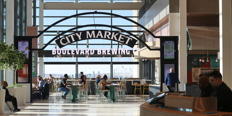 Large City Market sign with passengers sitting under it in the new terminal