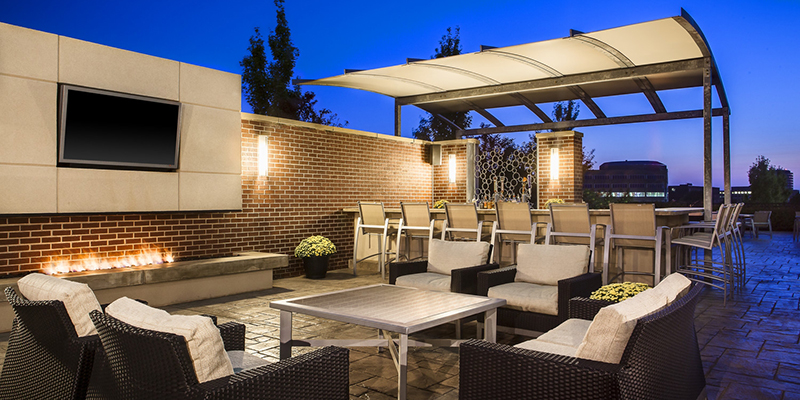 Five cushioned chairs surrounding a firepit on a hotel patio at dusk