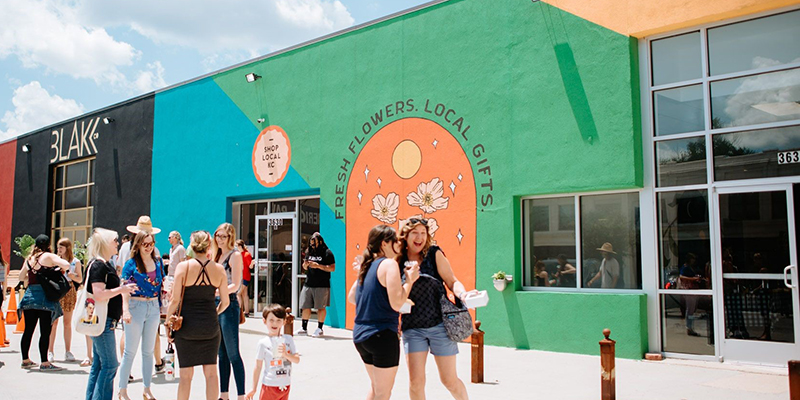 Exterior of Shop Local KC painted in blue, green, and yellow with shoppers in front