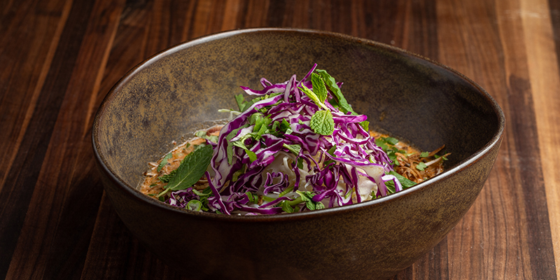 Noodle bowl with purple cabbage sitting on wooden table